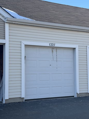 Front view of a garage with a white door and beige siding.