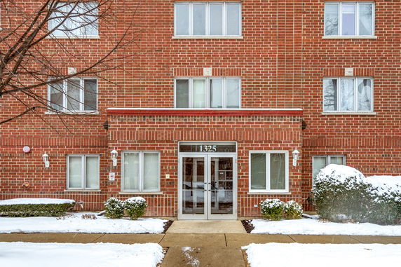 Front view of a multi-story brick building with multiple windows and a central entrance.