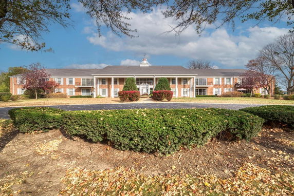 Front view of a large two-story building with brick facade and white columns.