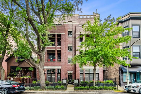 Front view of a multi-story brick building with balconies and trees.