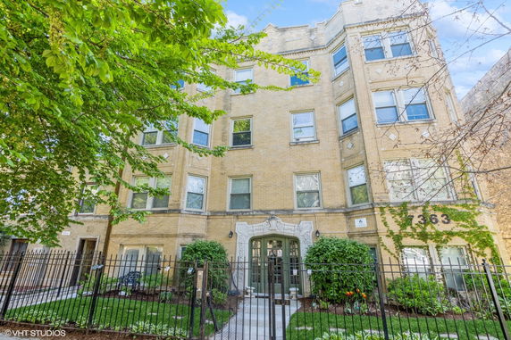 Front view of a multi-story brick apartment building with decorative entrance.