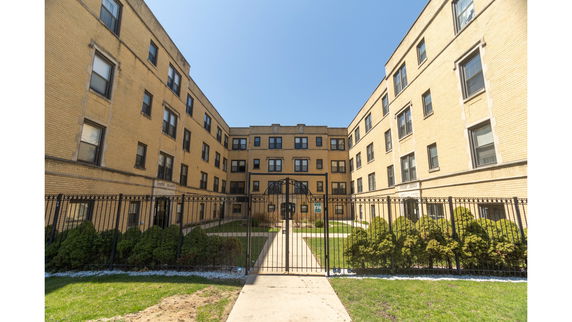 Front view of a multi-story apartment building with a gated entrance.