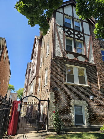 Front view of a multi-story brick building with a gated entrance.