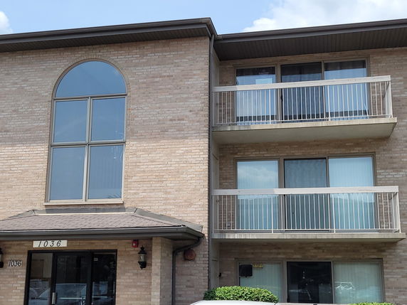 Front view of a multi-story building with balconies and large arched window.