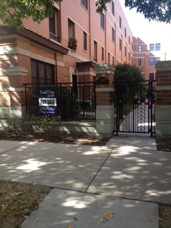 Front view of a multi-story brick building with a gated entrance.