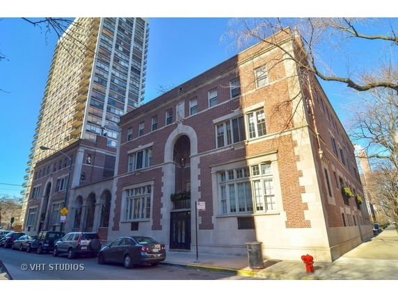 Front view of a brick building and a tall apartment building in an urban setting.