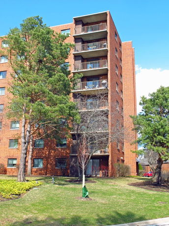Front view of a multi-story brick apartment building with balconies.
