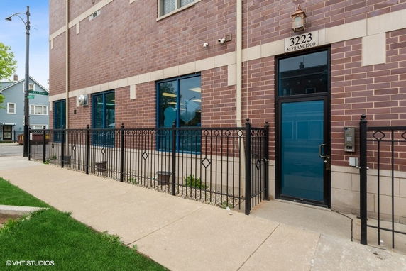Front view of a brick building with multiple blue windows and a blue entrance door.