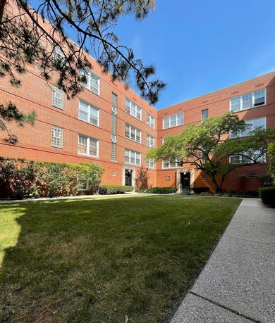 Front view of a brick apartment building with multiple floors and entrance doors.