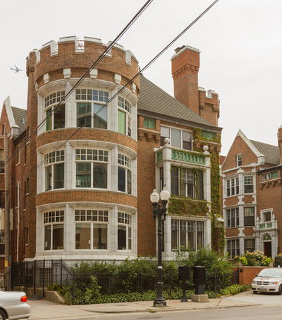 Front view of a multi-story brick building with round towers and large windows.