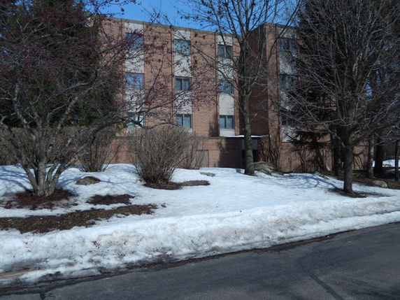 Front view of a multi-story brick building with snow on the ground.