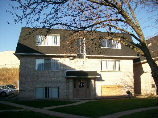 Front view of a two-story house with a dark roof and multiple windows.