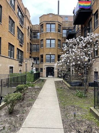 Front view of a multi-story apartment building with brick facade and multiple large windows.
