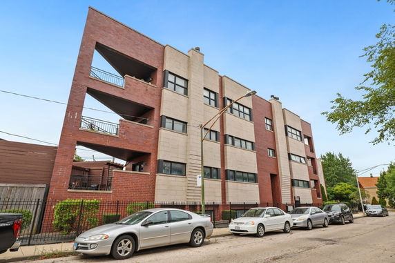 Front view of a multi-story apartment building with a modern design featuring angular balconies and brick facade.