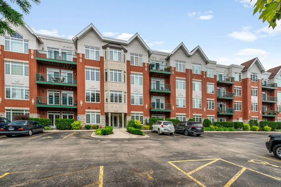 Front view of a multi-story brick apartment building with balconies and large windows.