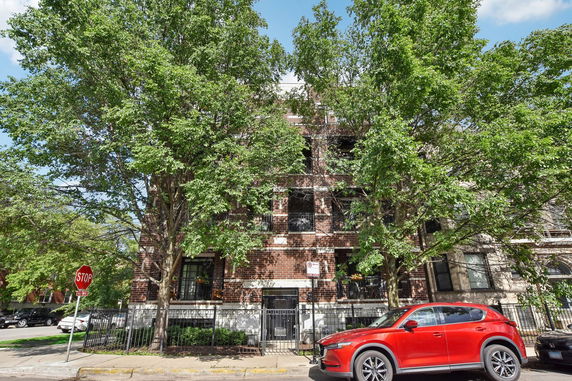 Front view of a multi-story brick building with large windows.