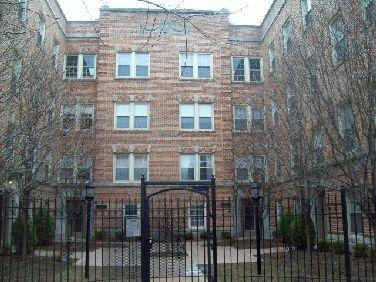 Front view of a multi-story brick apartment building with multiple windows.