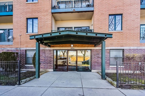 Front view of a multi-story brick building with balconies and a covered entrance.
