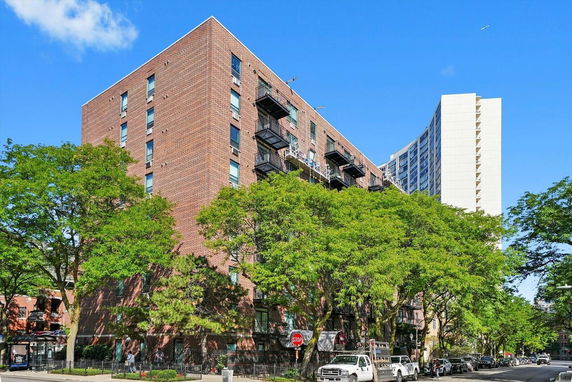 Front view of a multi-story brick apartment building with balconies.