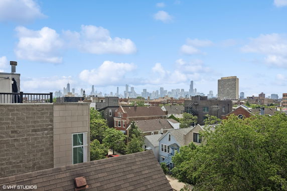 Panoramic view of a city skyline with residential buildings and trees in the foreground.
