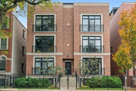 Front view of a multi-story brick building with balconies and a central entrance.