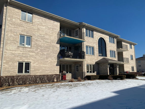 Front view of a multi-story brick apartment building with balconies.