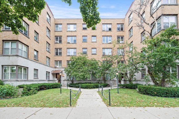Front view of a multi-story brick apartment building with multiple windows.