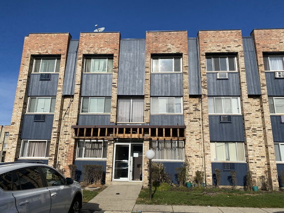 Front view of a multi-story apartment building with brick and blue paneling.
