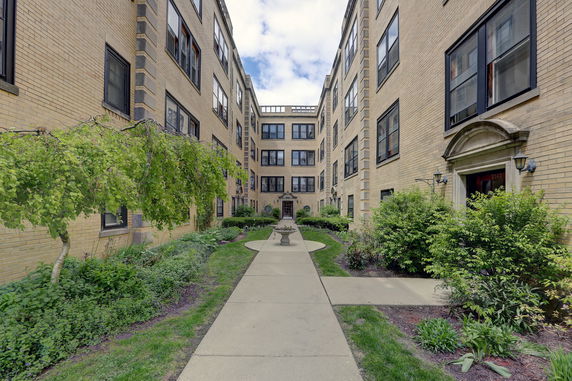 Front view of a multi-story brick apartment building with a courtyard.