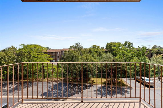 View from a balcony showing trees and distant buildings.