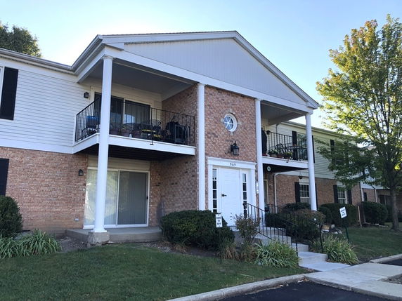 Front view of a two-story building with a brick and siding exterior featuring balconies and large white columns.