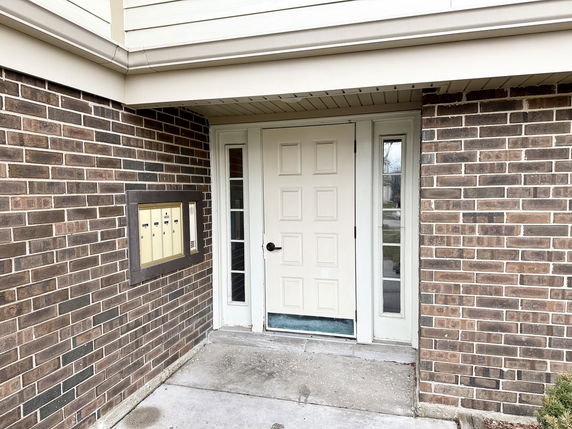 Front view of a house entrance with brown brick walls and a white door.