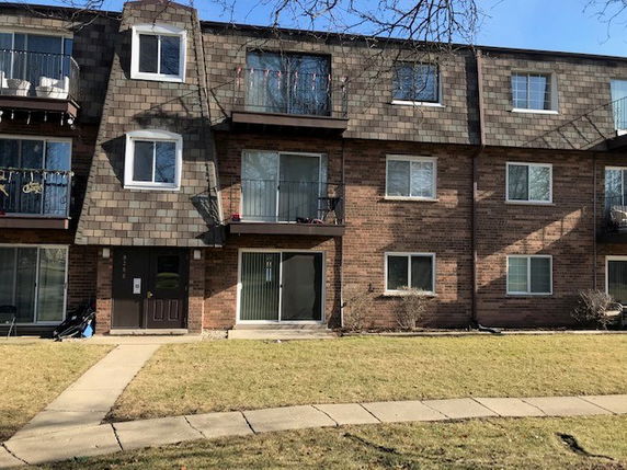 Front view of a multi-story residential building with brick facade and multiple balconies.