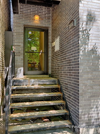 Entrance with stairs leading up to a door in a brick building.