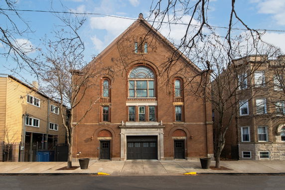 Front view of a brick building with large arched windows and a central entrance.