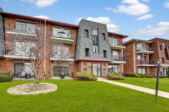 Front view of a multi-story brick apartment building with balconies.