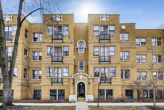 Front view of a multi-story brick apartment building with decorative elements.