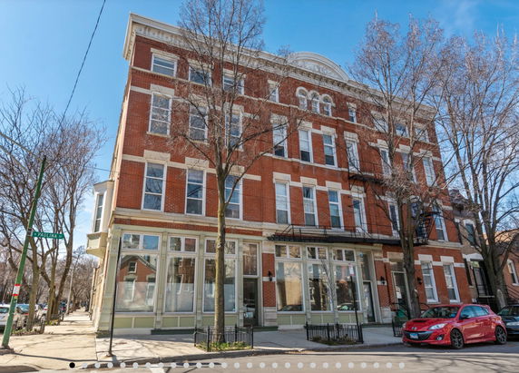 Front view of a multi-story brick building with large windows and a decorative facade.