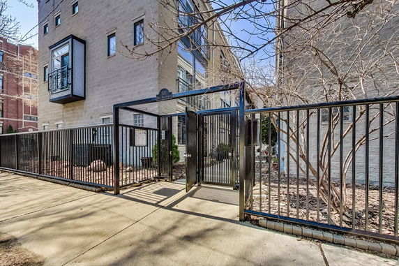 Front view of a building with a fenced entrance and a prominent window bay.