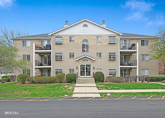Front view of a three-story apartment building with multiple balconies.