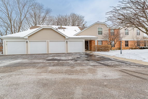 Front view of a two-story house with a three-car garage covered in snow.