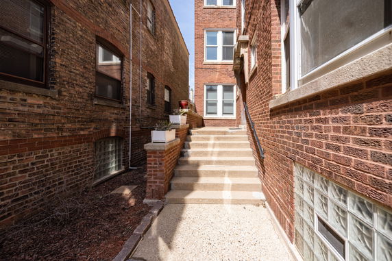 Exterior view of brick apartment buildings with a staircase leading to a doorway.
