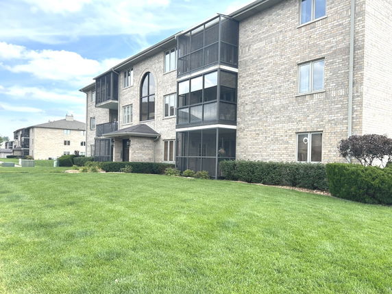 Front view of a multi-story brick apartment building with balconies.