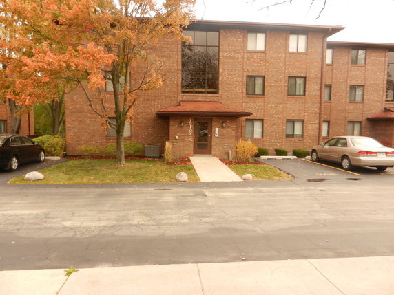Front view of a multi-story brick building with parking area.