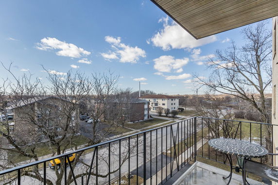 View from a balcony overlooking a residential area with buildings and trees.