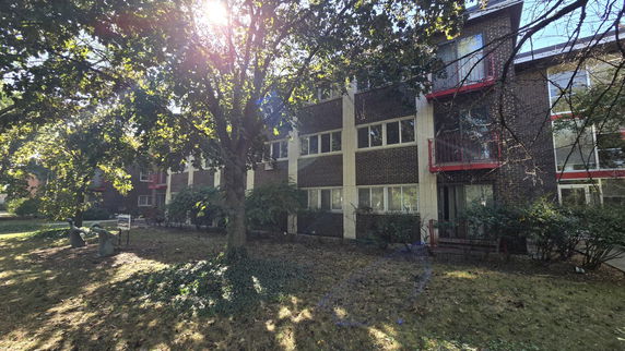Front view of a multi-story brick apartment building with balconies.