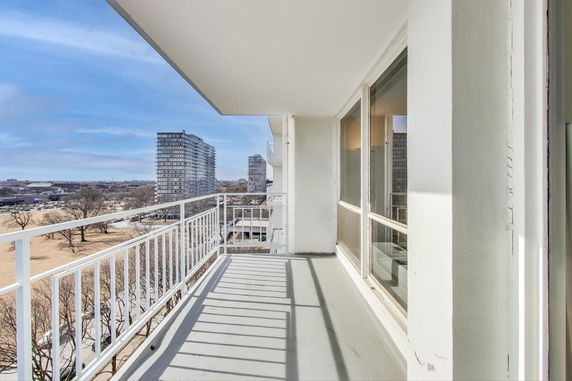 View of city buildings from a balcony with railing.