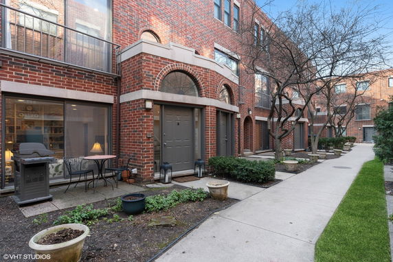 Front view of a brick townhouse with large windows and arched doorways.