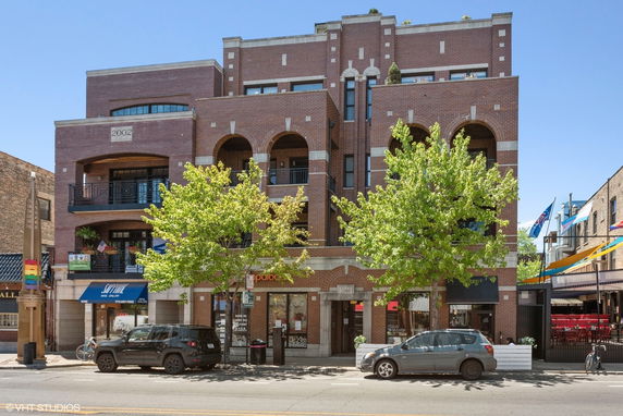 Front view of a multi-story brick building with multiple balconies and arched features.