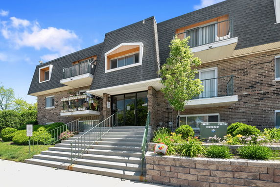 Front view of a multi-story residential building with brick exterior and balconies.
